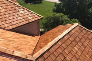 Image showing a residential house undergoing cedar roof replacement. Skilled workers are installing cedar shingles, ensuring precision and durability for the new roof.